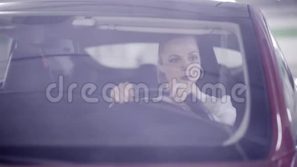 一个穿白衬衫的女孩坐在红色的车里车开始冒烟了视频的预览图