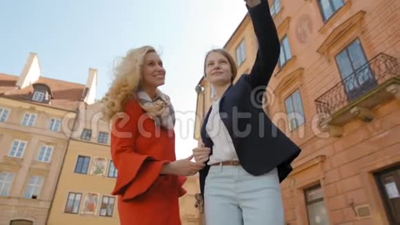 两个旅游女孩正在老城区用手机拍照自拍视频的预览图