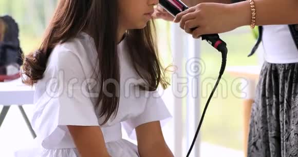 女理发师站着在美容院给可爱的亚洲青少年做发型视频的预览图