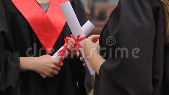戴着红丝带毕业证书的女毕业生的手谈话视频的预览图