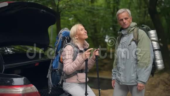 积极的老年夫妇站在森林里的汽车附近视频的预览图
