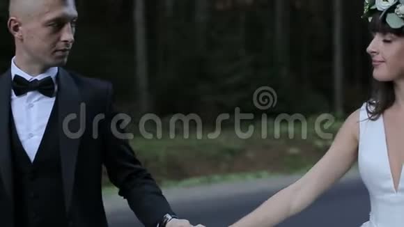 那人和他的新娘正牵着手沿着马路穿过高大的树视频的预览图