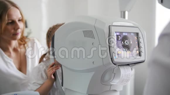 母亲和女儿在眼科医生的房间验光师在诊所检查小孩视力视频的预览图