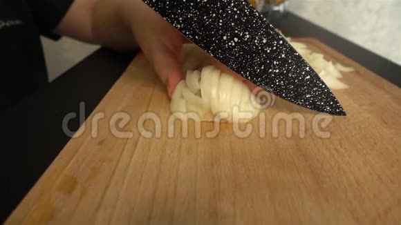 一把大刀正在厨房桌上的木板上慢慢切洋葱视频的预览图