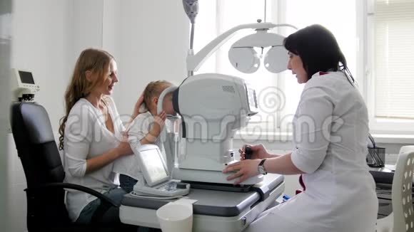 母亲和孩子眼科医生的房间里小女孩诊所里的验光师检查小孩视力视频的预览图