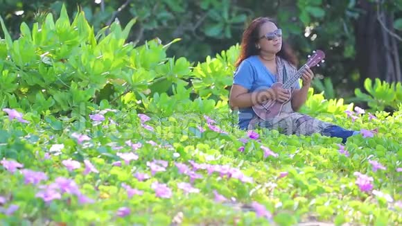 一个戴着太阳镜玩四弦琴的亚洲女人视频的预览图