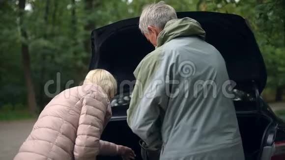 积极的老年夫妇从汽车行李箱中获得旅游设备视频的预览图