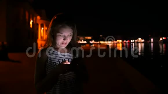 年轻女孩在后台夜空中的移动电话信使中写作视频的预览图