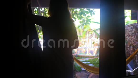 清晨的女孩打开窗帘打开阳台早上在热带地区视频的预览图