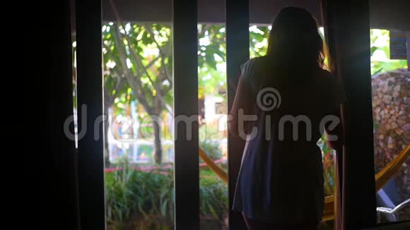 清晨的女孩打开窗帘打开阳台早上在热带地区视频的预览图