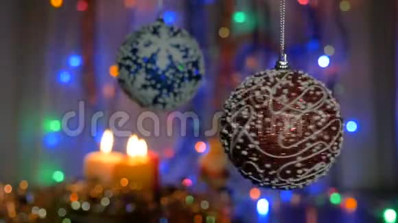 一个漂亮的红球在前景中旋转蓝球在模糊的背景上新年装饰点燃蜡烛视频的预览图