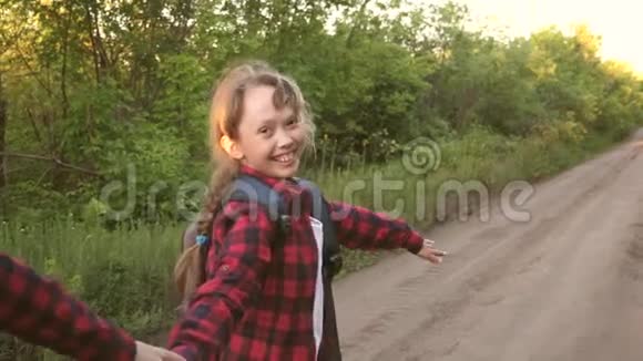儿童旅行者徒步旅行者女孩带着背包的快乐女孩旅行者牵着手沿着乡间小路奔跑概念视频的预览图