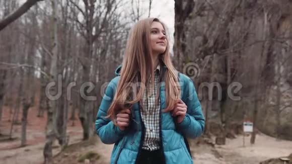 年轻迷人的金发女孩穿着休闲装背着背包穿过荒芜的森林享受着视频的预览图