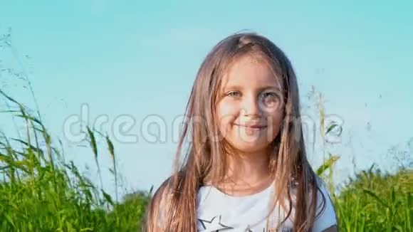 有魅力的小女孩的肖像有一双绿色的大眼睛在大自然的背景下头发正在发育视频的预览图