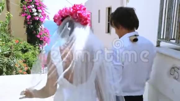 结婚纪念日新娘和新郎在一条鲜花盛开的美丽街道上出海视频的预览图