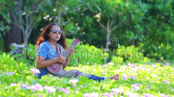 带着太阳镜在海滩上玩四弦琴的年轻亚洲女人视频的预览图