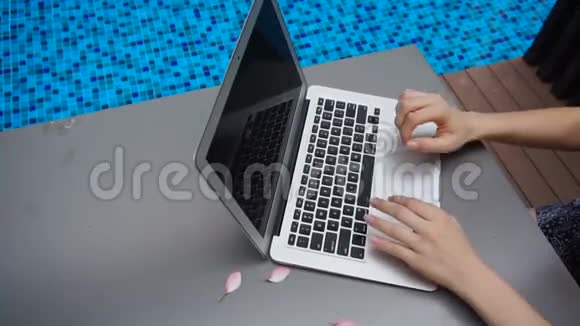 在游泳池附近的慢动作中在笔记本电脑键盘上闭上双手打字视频的预览图