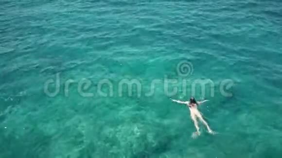 一名年轻女子在海里游泳的空中镜头视频的预览图