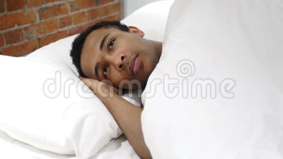 躺在床上思考和想象夜晚的非洲男人视频的预览图