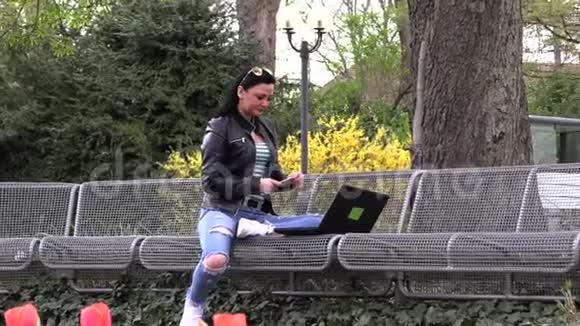 黑发女人坐在街凳上在电脑上工作视频的预览图