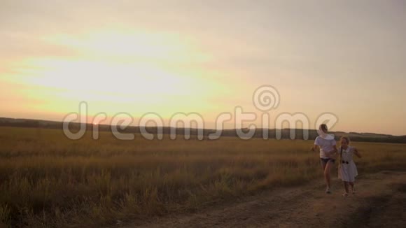 傍晚红日日落时快乐的孩子们沿着公路跑到田野慢动作视频的预览图