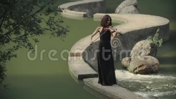 优雅的黑发小提琴家在户外的桥上演奏视频的预览图
