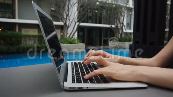 在游泳池附近的笔记本电脑键盘上以慢动作关闭双手打字视频的预览图