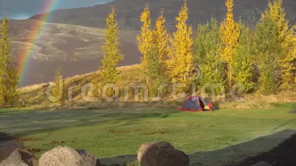 寒冷的橙色秋雾带着彩虹和帐篷在山上视频的预览图