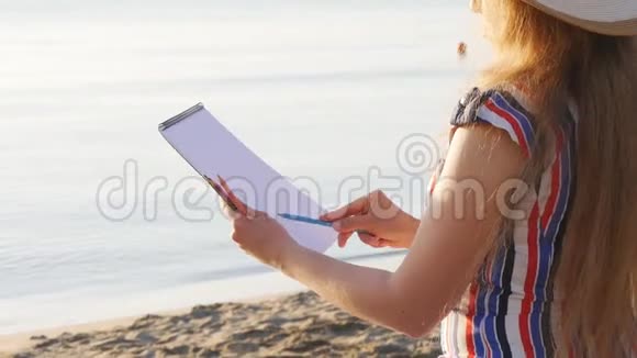 年轻女子正在海滩上画画视频的预览图