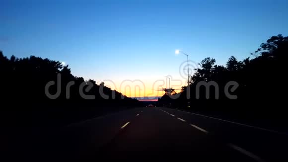 在日出期间驾驶乡村公路当太阳清晨在地平线上升起时司机的视角POV视频的预览图