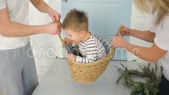 快乐的男孩在手工制作的篮子里玩得开心而他的父母却甩了他视频的预览图