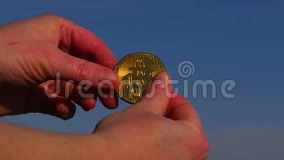 女人手里拿着比特币硬币对着蓝天视频的预览图