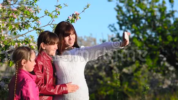 春暖花开的春天公园里母亲和孩子在看着母亲和女儿用电话给自己拍照视频的预览图