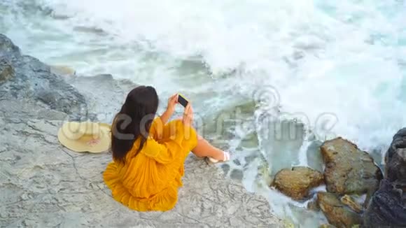 在海的悬崖上穿着衣服的年轻美女晚上在海滩上快乐的女孩视频的预览图