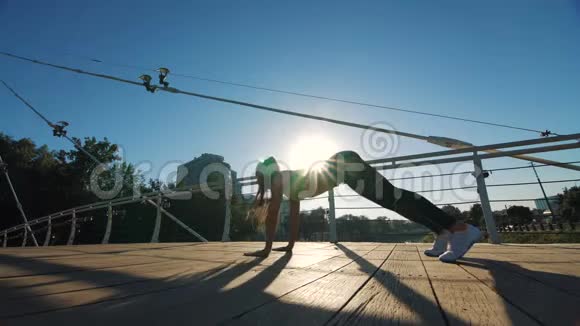 活跃的女性剪影锻炼和伸展在城市公园的人行天桥视频的预览图