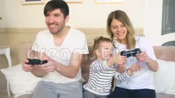 家庭幸福的父亲和母亲和儿子在家玩电子游戏视频的预览图