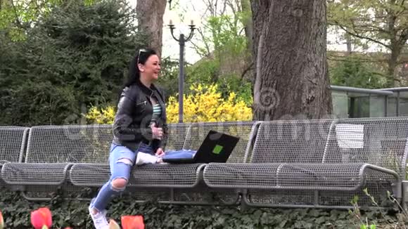 黑发女人坐在街凳上在电脑上工作视频的预览图