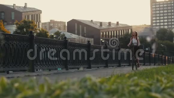 红发女子骑自行车在城市的背景立面建筑视频的预览图