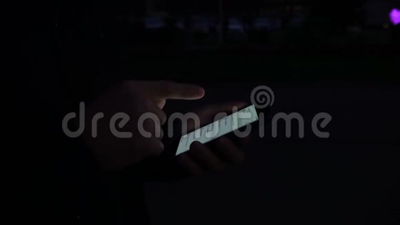 一个年轻人晚上在街上用智能手机的手视频的预览图