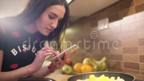 可爱的黑发女孩穿着睡衣刚在家做早餐她拍了一些不同食物的照片视频的预览图