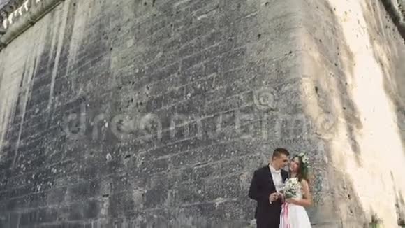 漂亮的新婚夫妇拥抱在城堡墙附近视频的预览图