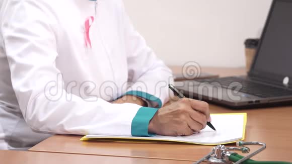 一名女医生在工作时用手提电脑写笔记的镜头视频的预览图