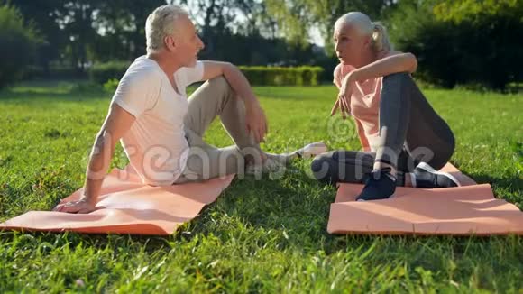 快乐的老年运动夫妇坐在运动垫上视频的预览图