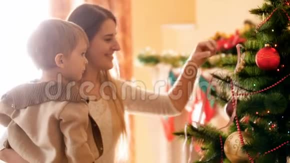 快乐的年轻妈妈和她的小男孩在客厅装饰圣诞树视频的预览图