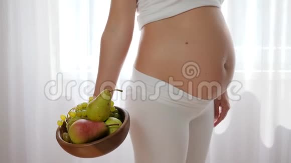 腹部有婴儿的贴身女人在盘子里放梨和水果视频的预览图