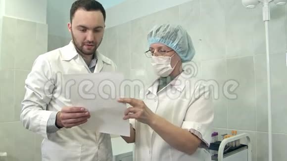 男医生与口罩护士讨论医疗报告视频的预览图