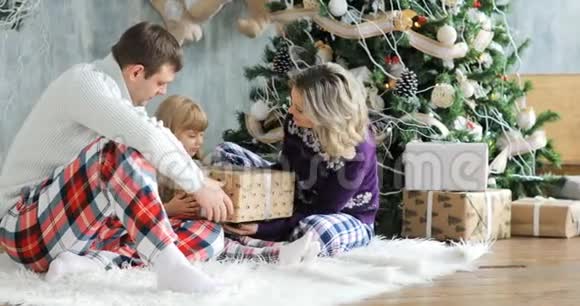 父母和女儿在客厅里玩圣诞礼物盒子里有圣诞礼物给孩子A视频的预览图