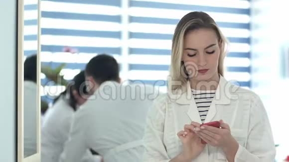 漂亮的护士使用手机另一个护士清洁接待处视频的预览图