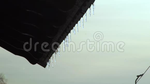 融化冰柱悬挂在边缘屋顶在冬季天空景观从春天闪耀融化的冰柱上偷听视频的预览图
