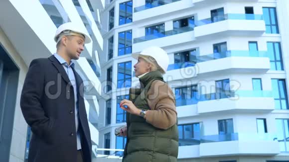 一个戴着白盔的男人和女人正在谈论一栋建筑的背景视频的预览图